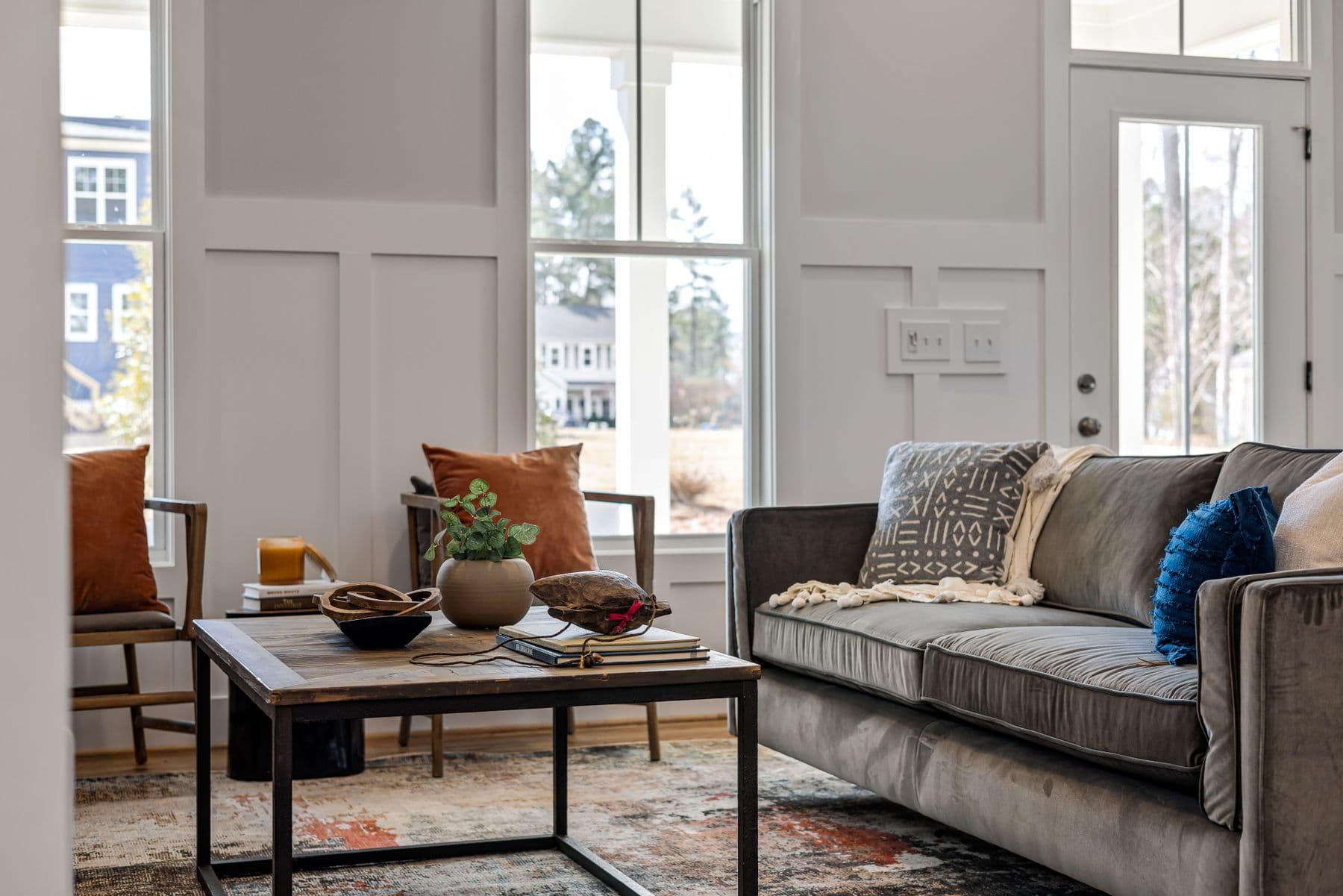 A calm, naturally lit living room with warm wood and neutral furnishings